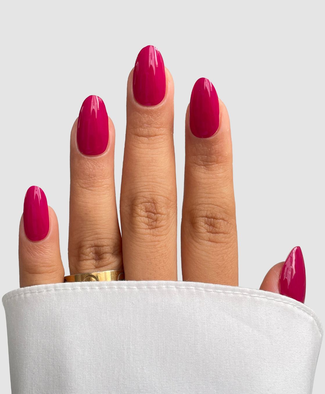 A hand with neatly manicured nails featuring Sassy Saints' Rosewater Silk Gel Wrap is shown against a light gray background. A gold ring adorns the middle finger, and a white cuffed sleeve partially covers the base of the fingers.