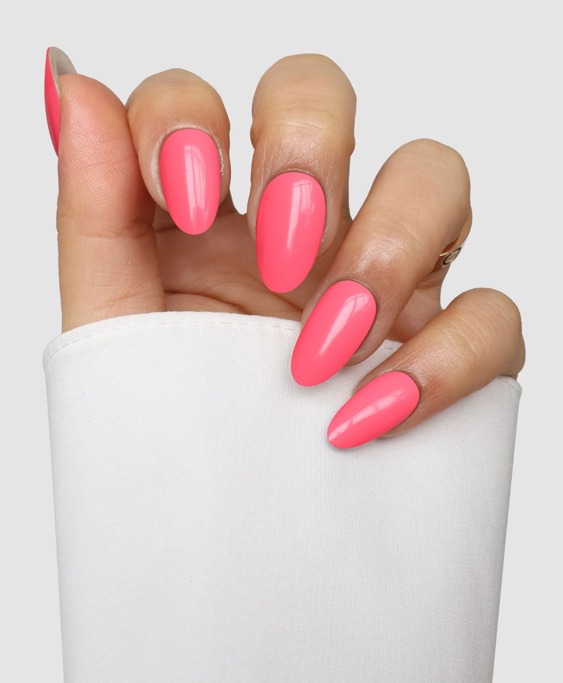 A hand with long, almond-shaped nails features Sassy Saints' Candy Chaos Gel Wraps in bright pink. The fingers are slightly curled, and the person is wearing a white sleeve against a plain background.