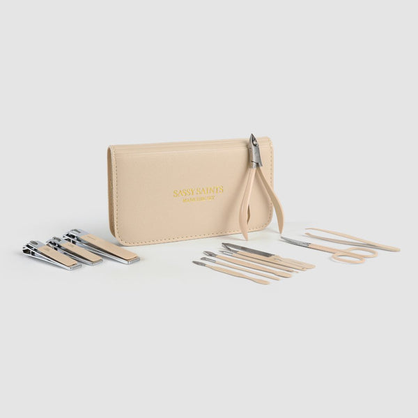 A beige Manicure Tool Kit case, branded Sassy Saints - Brings The Salon Home, is surrounded by neatly arranged clippers, scissors, tweezers, and cuticle pushers for easy at-home nail care.