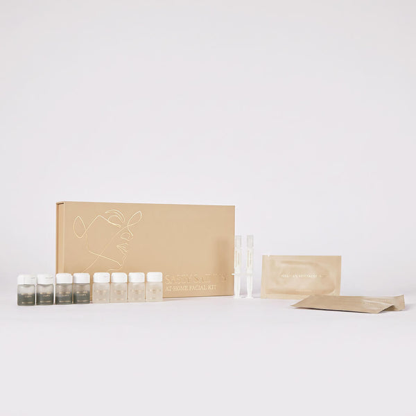 A beige Bio-Microneedling Facial Kit by Sassy Saints – Brings The Salon Home, featuring vials, packets, and a box arranged neatly on a white background.