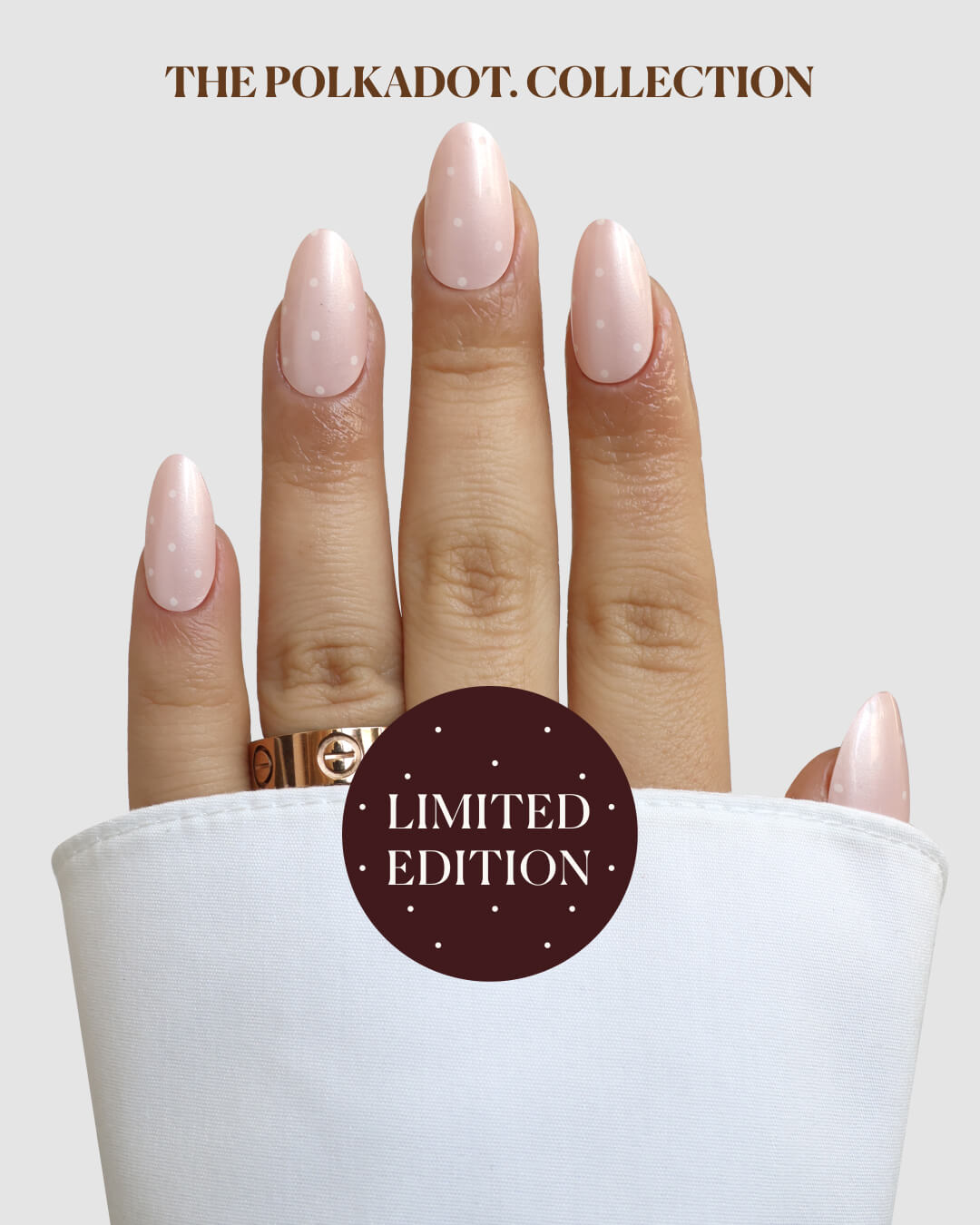 A hand with almond-shaped nails features Saintly Sweet Gel Wrap by Sassy Saints - Brings The Salon Home in soft pink with white polka dots, wearing a gold ring and white cuff. Text reads SAINTLY SWEET GEL WRAP and LIMITED EDITION on a brown circle.