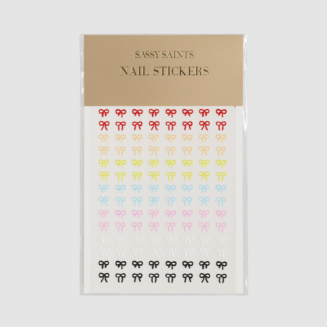 A sheet of Multi Colour Bows Nail Stickers by Sassy Saints - Brings The Salon Home, featuring small bow-shaped stickers in various colors under a beige label.