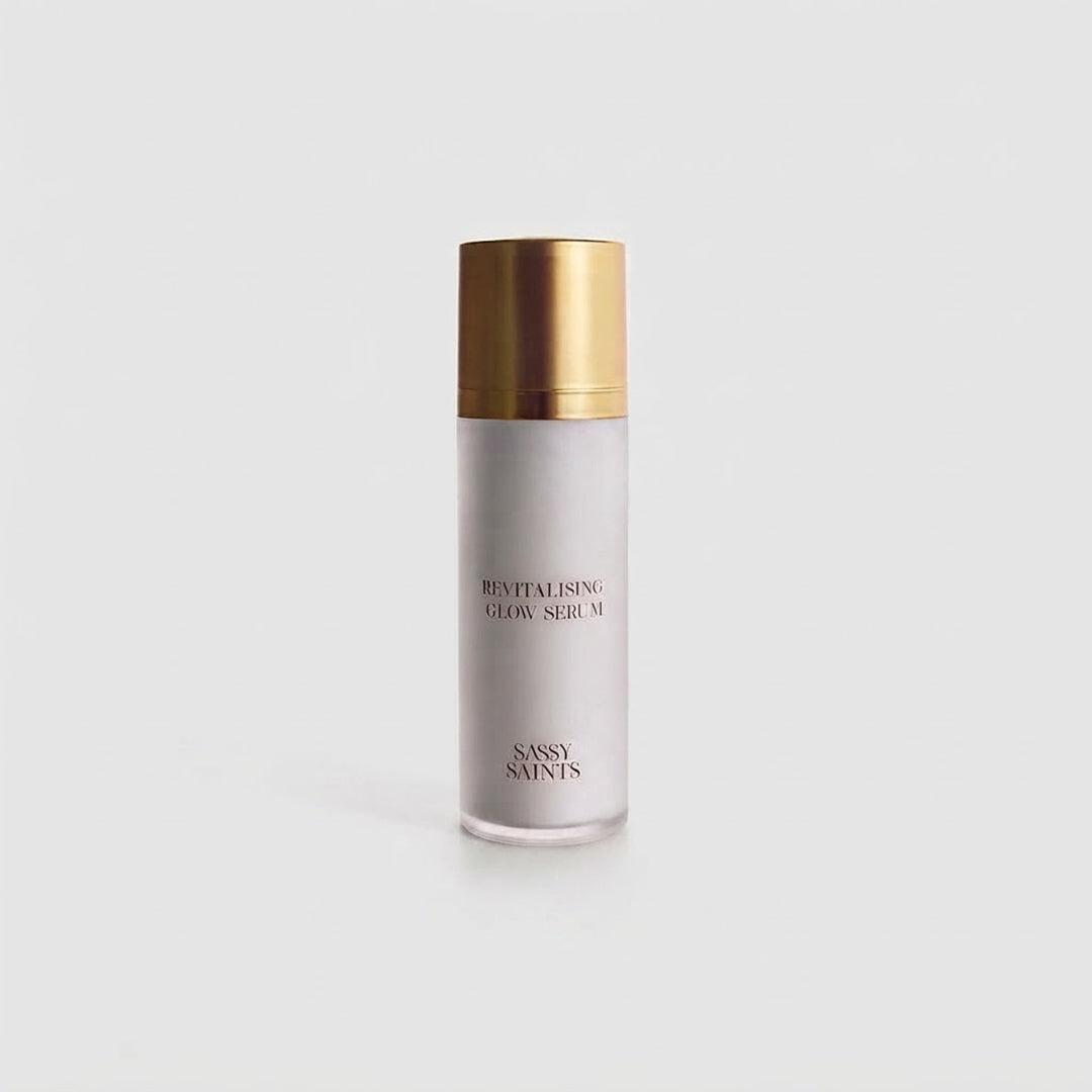 A white bottle with a gold cap labeled Revitalising Hand Serum and Sassy Saints – Brings The Salon Home stands upright on a plain white background.