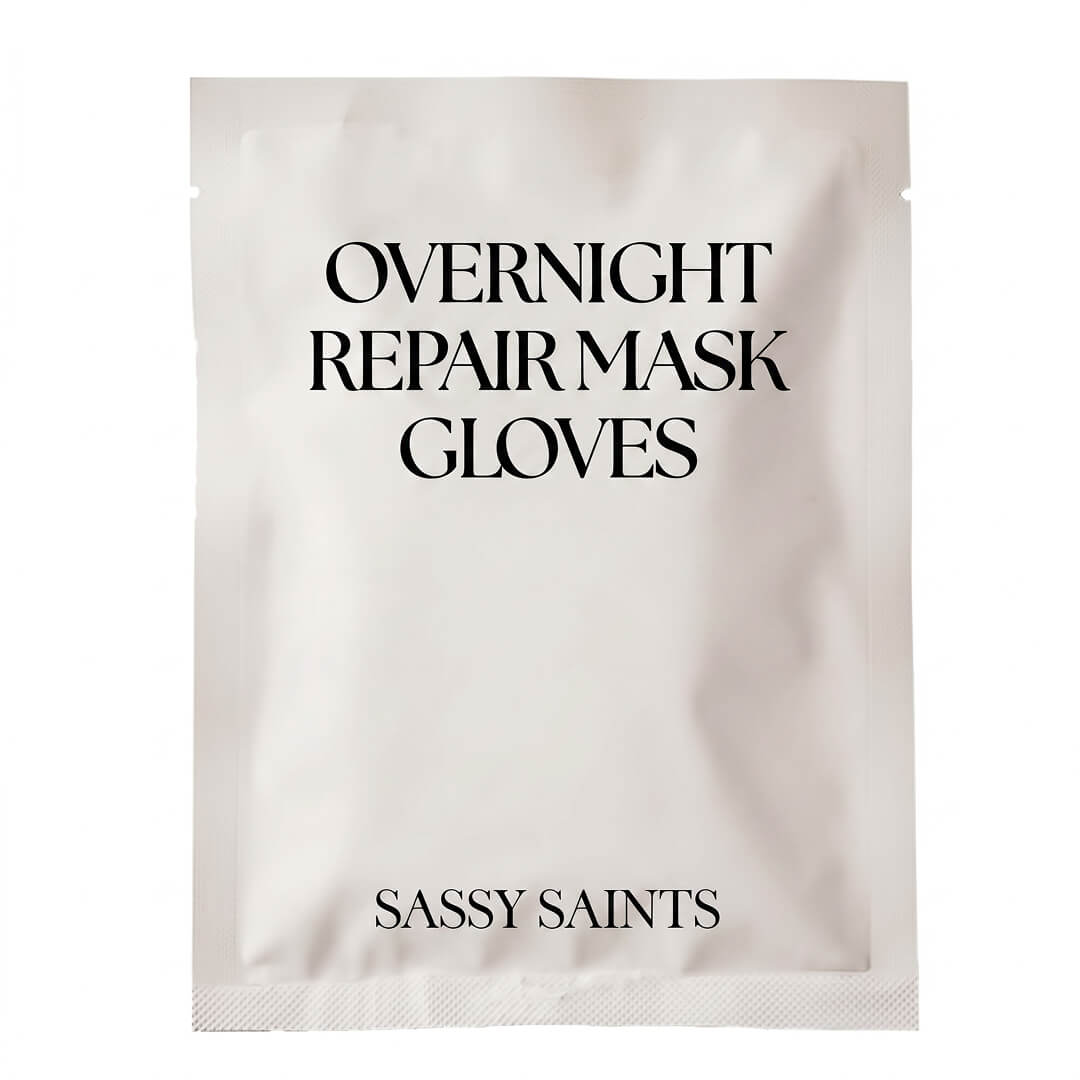 A white packet labeled Overnight Repair Mask Gloves features the brand name Sassy Saints – Brings The Salon Home at the bottom in black text.