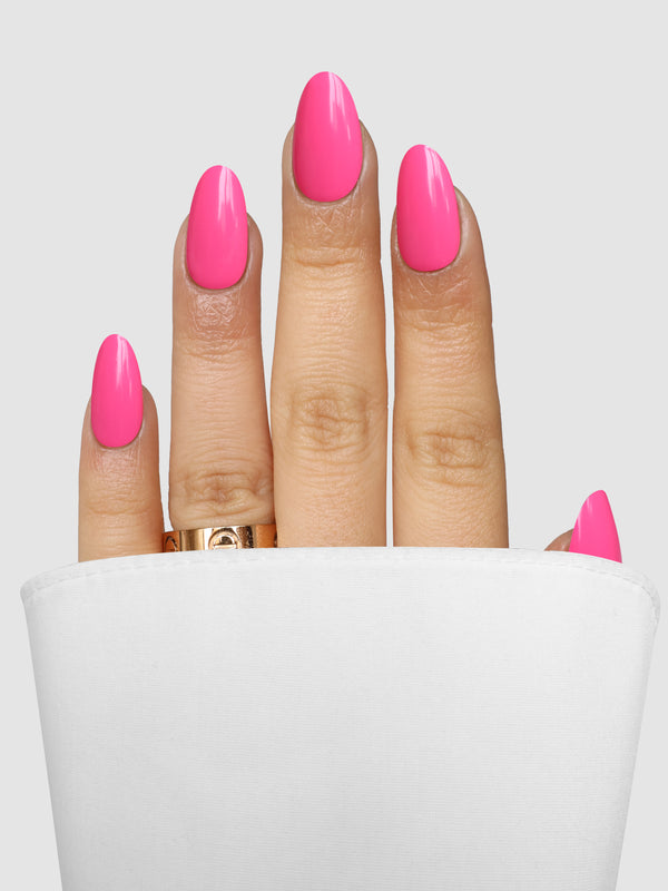 A hand with almond-shaped nails wearing Pink Problem Gel Wrap in a bright pink polish and a gold ring on the ring finger.