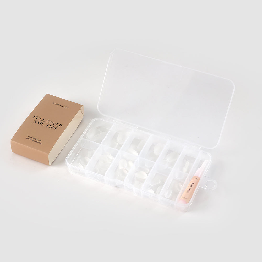On a light gray background, Sassy Saints Oval Full Tips are displayed in a compartmentalized plastic case alongside a small tube of nail glue.