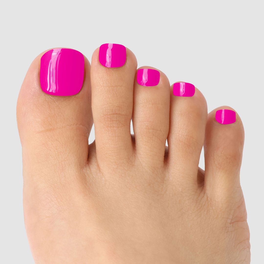 A close-up of a foot with toenails coated in Sassy Saints’ Pink Hype Pedicure Gel Wrap, showcasing glossy bright pink nails against a plain light gray background.