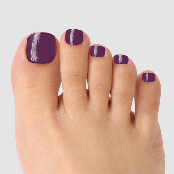 A close-up of toes adorned with Sassy Saints' Bare Mulberry Pedicure Gel Wrap, featuring glossy purple nails against a plain light gray background.