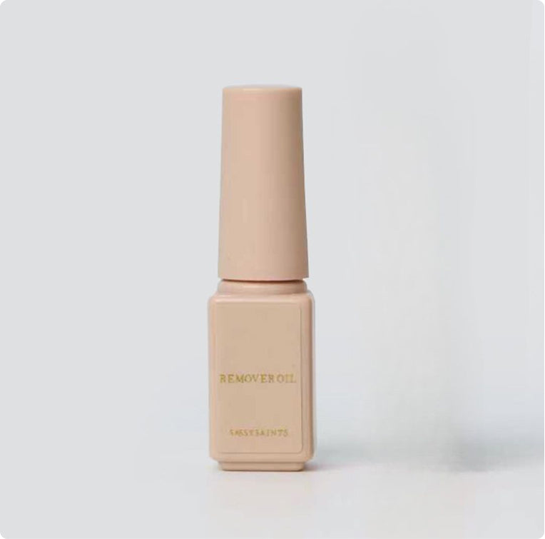 A beige bottle with a long cap labeled "Gel Wrap Remover Oil" by Sassy Saints - Brings The Salon Home stands upright against a plain light gray background.